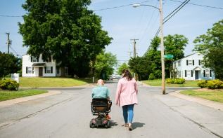 a woman walking with a man in a wheelchair 